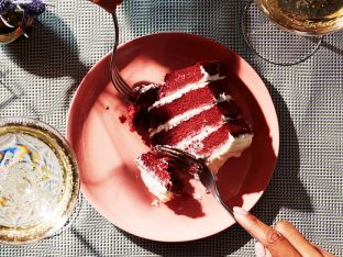 couple taking bite out of slice of red velvet cake