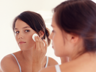 Teen girl wiping her face with a cotton pad