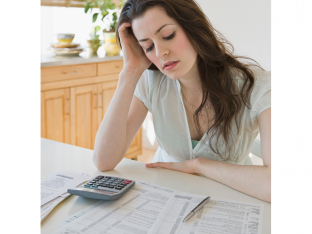 Woman looking frustrated at tax paperwork