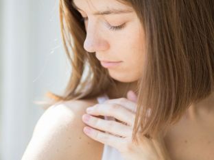 woman inspecting rash on shoulder