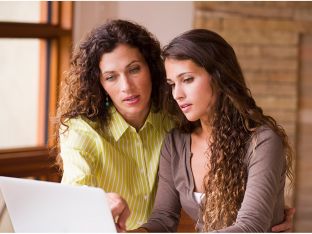 mom and teen daughter talking over laptop
