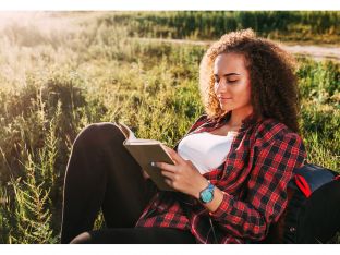 teen girl reading book in a meadow