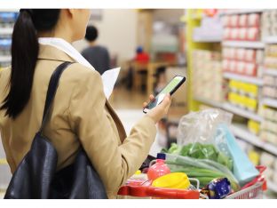 woman grocery shopping with phone and paper list
