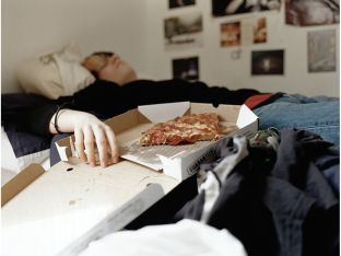 Boy sleeping with pizza on bed