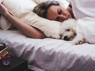 woman and her dog comfortably sleeping in the bed