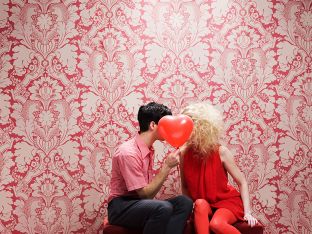 young couple behind a heart-shaped balloon