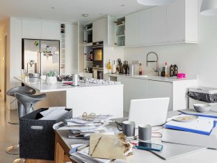 cluttered white kitchen with piles of mail
