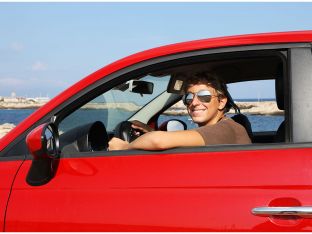 teen boy driving red car wearing sunglasses