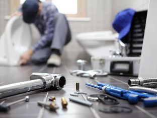 plumber at work in a bathroom installing toilet