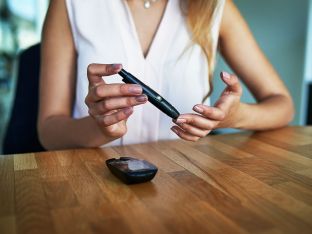 diabetic woman testing her blood sugar level in an office