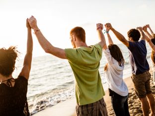 teen volunteers with arms raised on beach