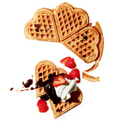 sweet heart waffles topped with strawberries chocolate syrup and whipped cream
