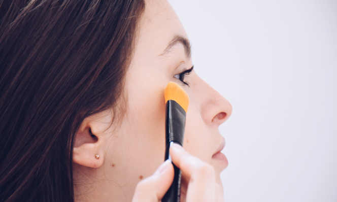 Teen girl applying concealer