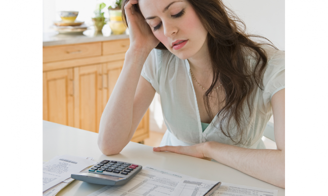 Woman looking frustrated at tax paperwork