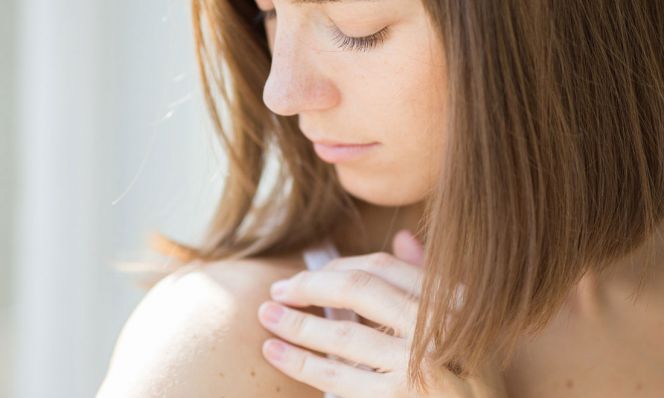 woman inspecting rash on shoulder