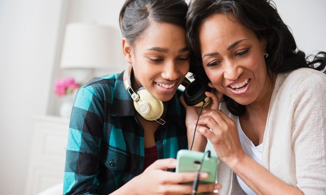 Mother and daughter listening to cell phone music on headphones