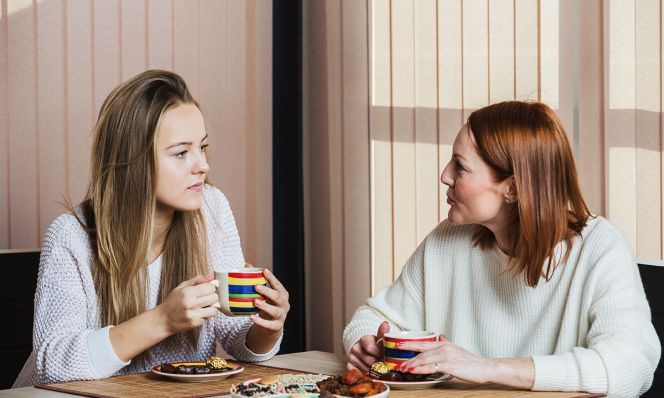 Mother and daughter talking while having breakfast at home