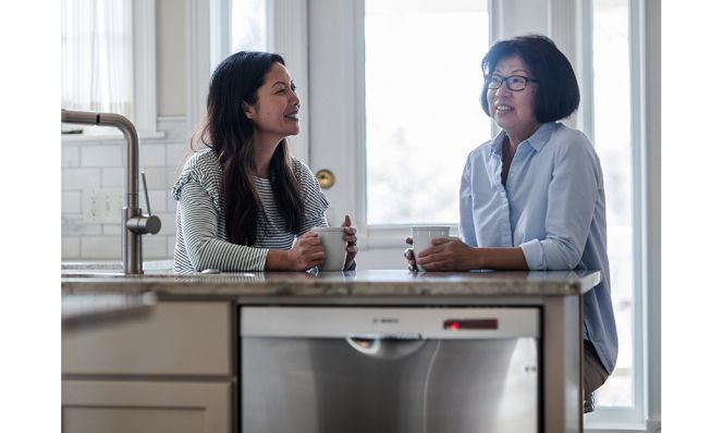 mom and adult daughter having coffee in kitchen