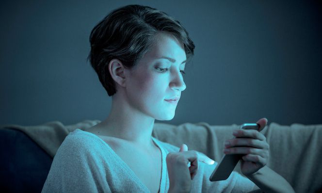 woman scrolling on phone in dark room