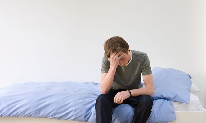 anxious teenage boy sitting on bed